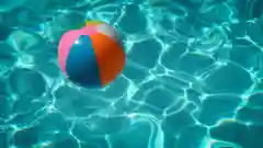 A colorful beach ball floating in a bright blue swimming pool.