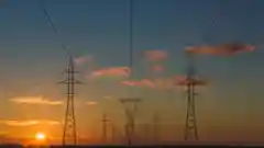 Electrical power lines stretching into the distance at sunset.