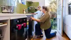 A woman and a child looking at a dishwasher with an energy star rating label in a kitchen.
