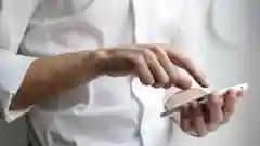 A person in a white shirt using a smartphone to manage home utilities.