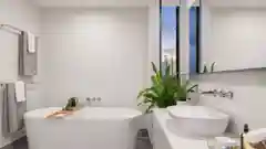 A modern bathroom featuring a white freestanding bathtub, basin, and a green plant.