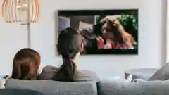 A modern, sleek flat-screen television displaying a vibrant, high-definition colorful background in a brightly lit room.