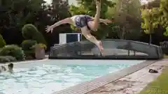 A young boy mid-air while diving into a clear blue swimming pool.
