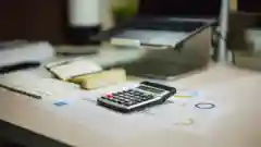 A calculator resting on financial documents and charts on a desk.