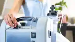 Close-up of a person's hands adjusting the dial on a home medical oxygen concentrator machine.