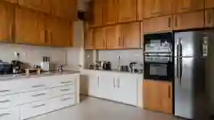 Modern kitchen with white lower drawers, wooden upper cabinets, a built-in double oven, and a refrigerator.