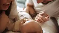 A happy mother and father smiling as they look down at their new baby.