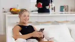 A woman on her phone as she sits on the sofa