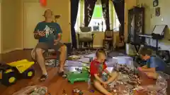 A father and two young boys playing with toys on a living room floor.