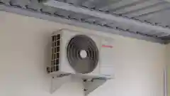 A white Sharp brand outdoor air conditioner compressor unit mounted on a wall bracket under a metal corrugated roof.