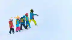 A group of five children in colorful winter gear skiing together on a snowy slope.