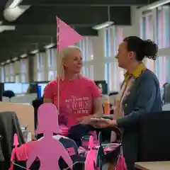  Two women chat at a BCNA Pink Bun fundraiser cart in an office
