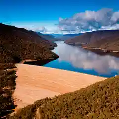 High-angle aerial view of Talbingo Dam and reservoir surrounded by forested mountains in the Snowy Mountains, NSW.