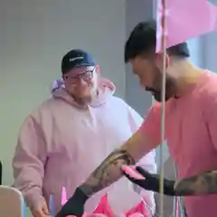 Two men in pink hoodies prepare pink buns at a BCNA fundraiser cart.