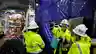 Team of workers in hi-vis gear and hard hats reviewing plans inside an underground tunnel construction site