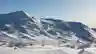 Snow-covered mountain slopes at Thredbo on a clear blue-sky day, with ski runs and a chairlift visible.