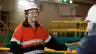Worker in orange hi-vis gear smiling during a conversation inside an industrial power station with yellow railings