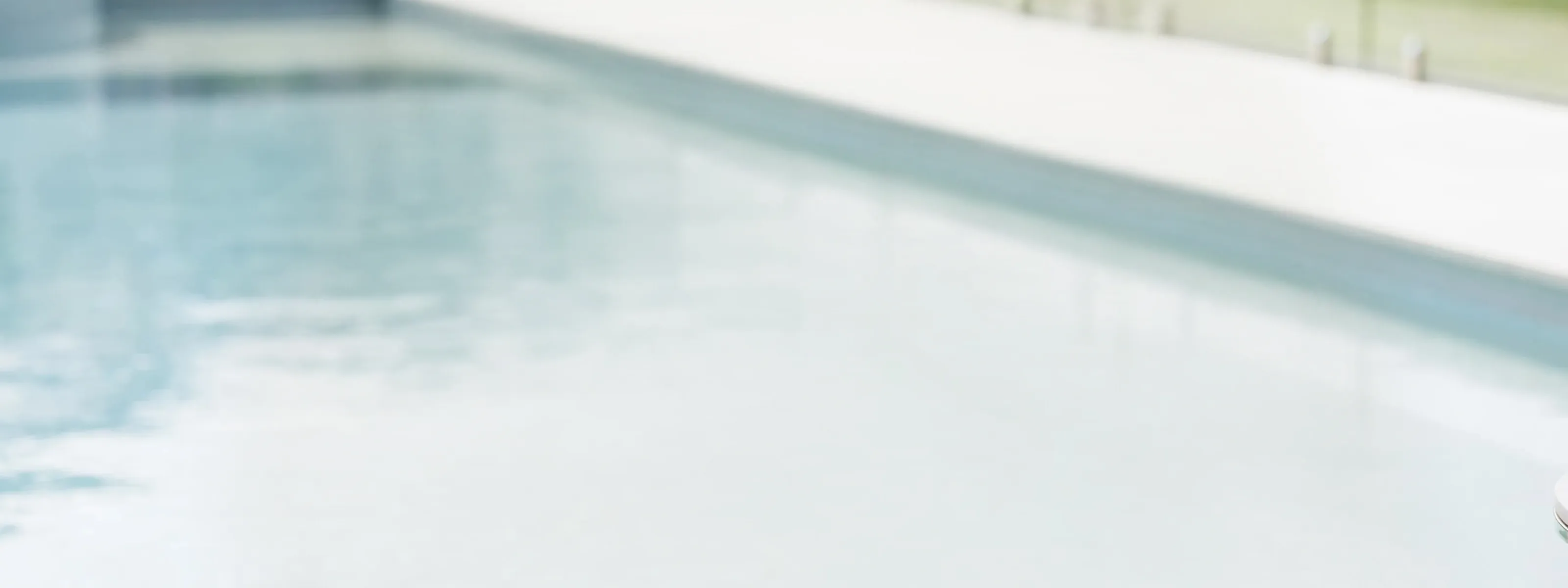 A woman in a red bathing suit sits by the side of pool on a sunny day.